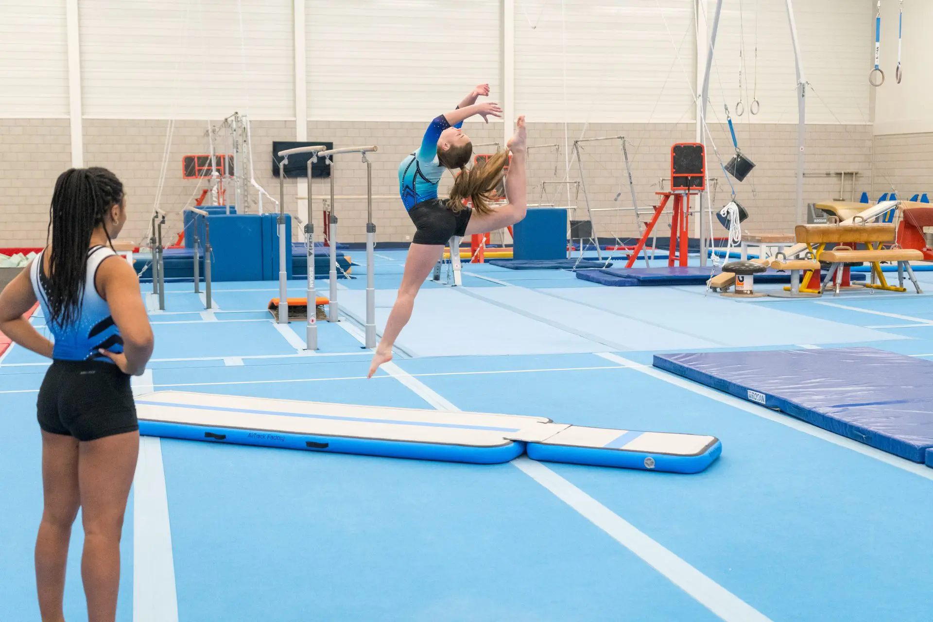 Gymnast leaping on blue inflatable AirFloor and AirBoard