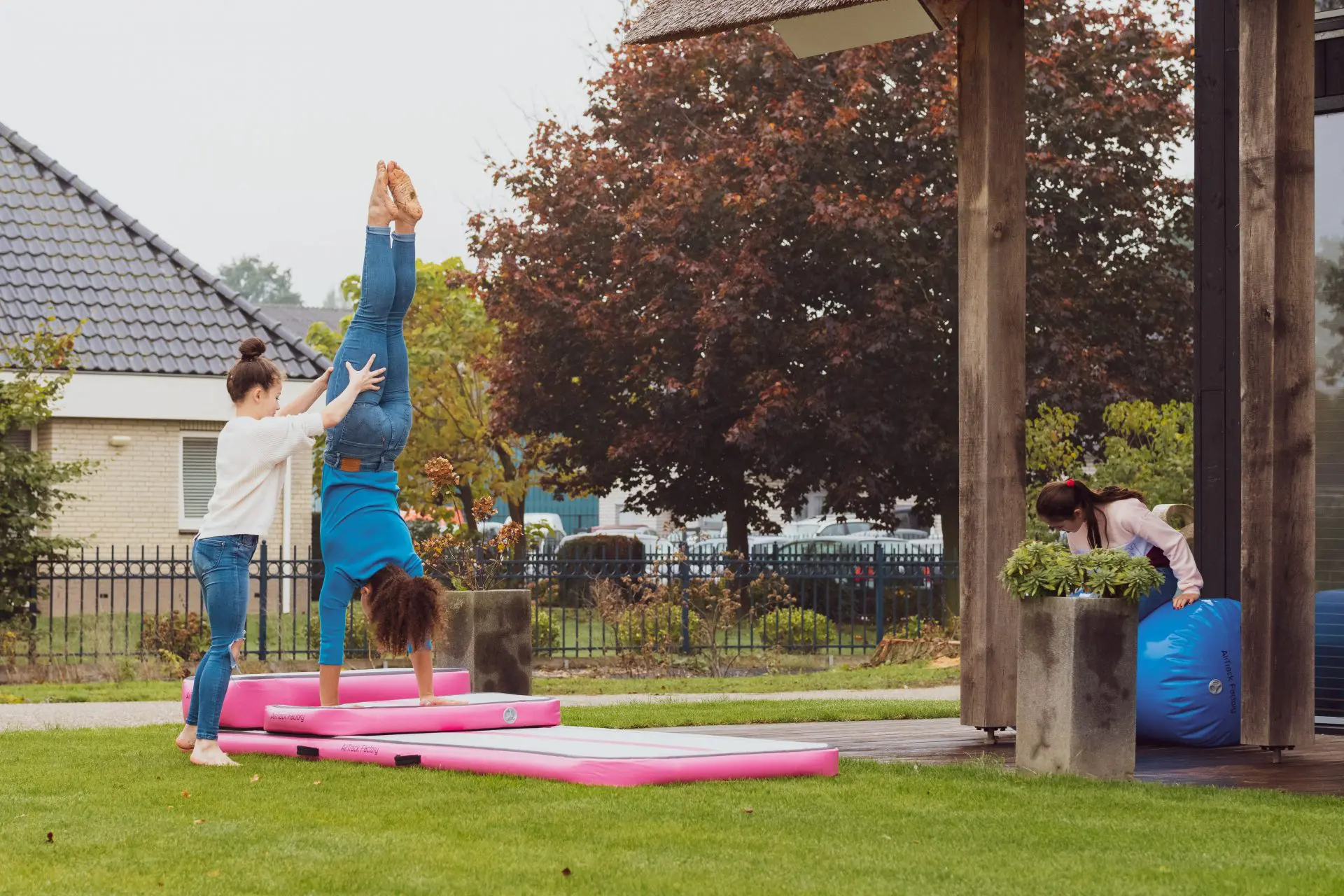 2 girls practicing gymnastics on pink inflatable AirTrack 3 meter training set in garden